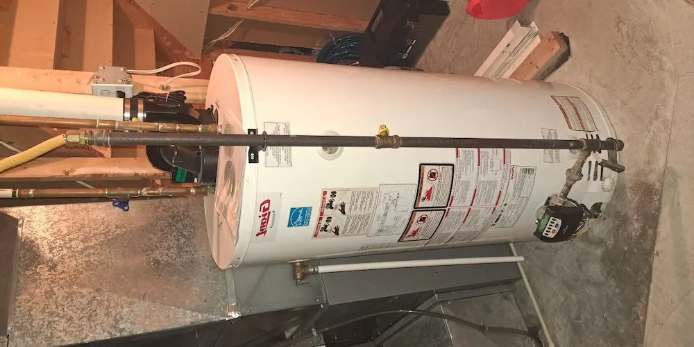 A large white "Giant" brand gas water heater in a basement, showing safety labels, an Energy Star logo, and a gas control valve at the bottom.